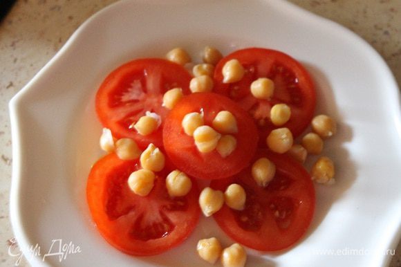 Выкладываем на тарелку кольца помидоров, сверху посыпаем нутом, солим, перчим.
