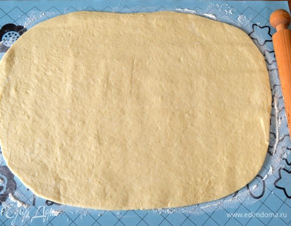 Подошедшее тесто выложить на рабочую поверхность и раскатать в прямоугольный пласт толщиной примерно 0,5 см. 