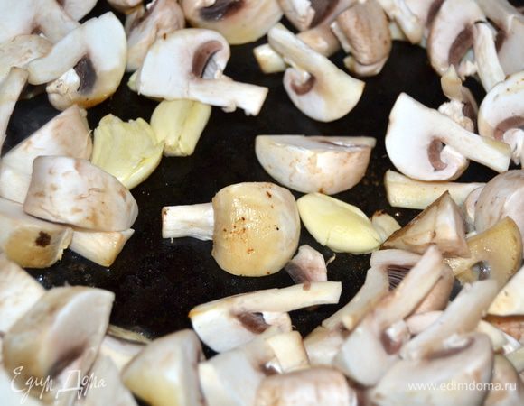В сковороду отправьте нарезанные дольками шампиньоны и раздавленный плоской строной ножа чеснок. Обжарьте.