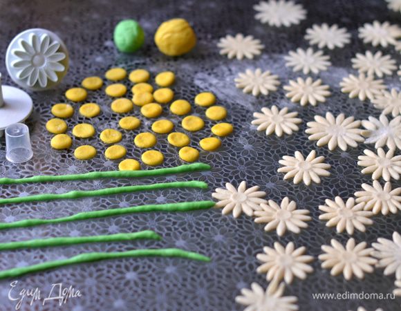 За 5 минут до готовности пирога сделаем украшения. Тесто раскатать тонко, с помощью плунжера вырезать ромашки. Отщипнуть от теста 2 небольших кусочка. Добавить в них пищевые красители - зеленый и желтый. Помять тесто в руках, чтобы красители распределились равномерно. Тесто становится похожим на эластичную воздушную массу, которую очень приятно держать  в руках. Вырезать кружки подходящего размера под ромашки - это будет сердцевина цветка. Из зеленого теста скатать несколько стебельков.