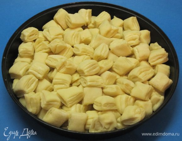 Форму (у меня круглая форма диаметром 24 см) смазать маслом. Выложить кубики из теста в форму. Лучше сначала на дно уложить кусочки теста, которые были по краю круга, то есть те, которые имели произвольную форму. А сверху уложить красивые ровные кубики.