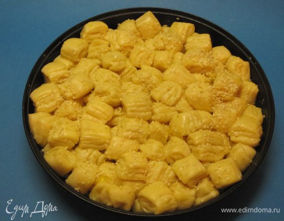 Накрыть форму пищевой пленкой и оставить на 30 минут. Желток слегка взбить с 10 мл молока, аккуратно смазать верх пирога. Сверху посыпать кунжутом.