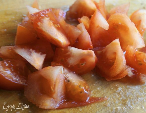 Помидор промыть и нарезать крупными ломтиками, которые затем разделить пополам.