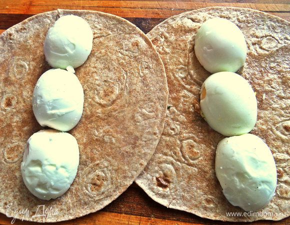 Выстраиваем на каждую тортилью посередине половинки яиц, сколько уместится. Если взять лаваш, то уместятся все в ряд.