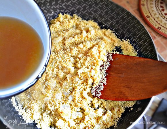 Выключить огонь, добавить кускус и перемешать. Влить горячий куриный бульон, накрыть сковороду крышкой и дать постоять 5-7 минут.