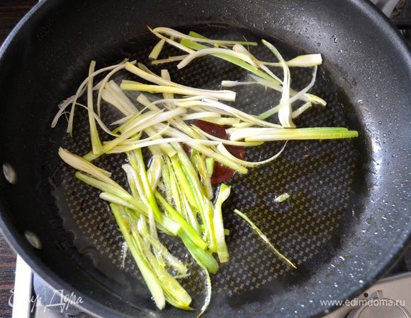 В сковороде нагреть 2 ст.л. оливкового масла и добавить нарезанный полосочками зеленый лук. Обжаривать минуту, помешивая, чтобы лук не пригорел. 