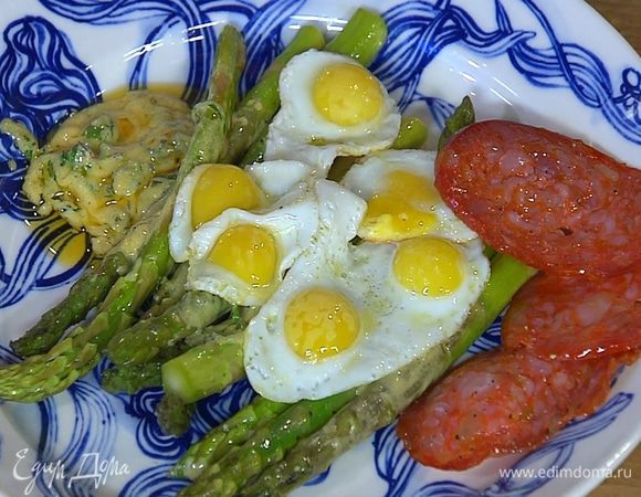 Выложить спаржу вместе с соусом на тарелку, сверху поместить перепелиные яйца и кусочки колбасы.