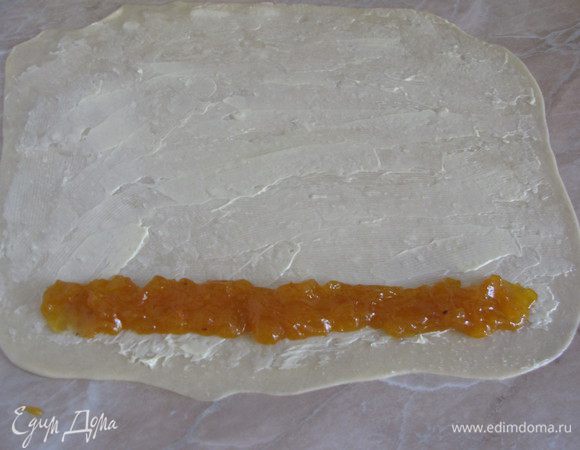 Каждую часть раскатать в очень тонкий прямоугольный пласт, примерно 25х30 см. Рабочую поверхность, на которой будем раскатывать тесто, обязательно смазать растительным маслом. Подготовленное тесто обильно смазать размягченным сливочным маслом. На одну длинную сторону выложить начинку.