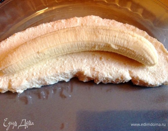 В творог добавить сметану и сахар, ванильный порошок, апельсиновую цедру и хорошо все перемешать, выложить подушку из смеси по форме банана как на фото, сверху положить очищенный целый банан.