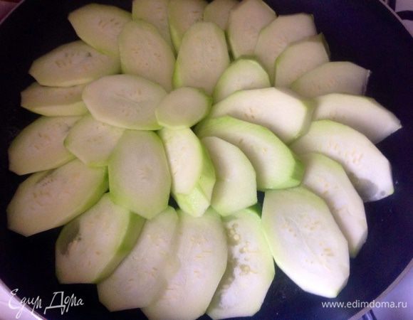 Растопить кусочек сливочного масла на сковороде, почистить от кожуры кабачок, порезать на кружочки и выложить внахлест, посолить.