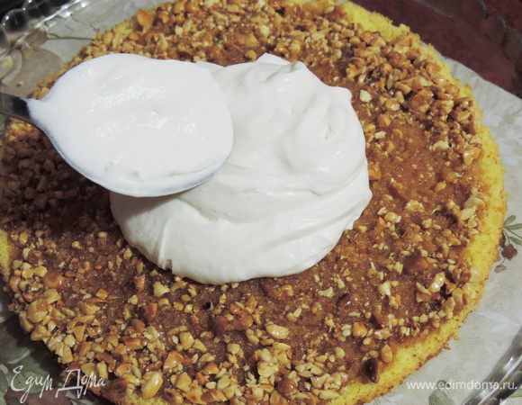 Кладем на блюдо пласт бисквита с карамелью и арахисом. смазываем его приблизительно третью крема, далее чередуем, корж-крем.