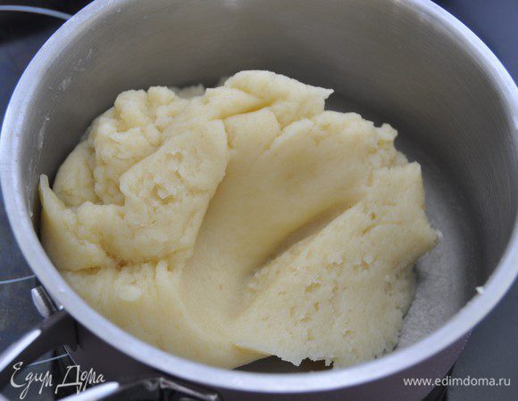 Просеянную муку добавить в сотейник и быстро вымешать до однородного теста. Размешивать ложкой, пока тесто не начнет отставать от стенок сотейника (1-2 минуты). Снять с огня.
