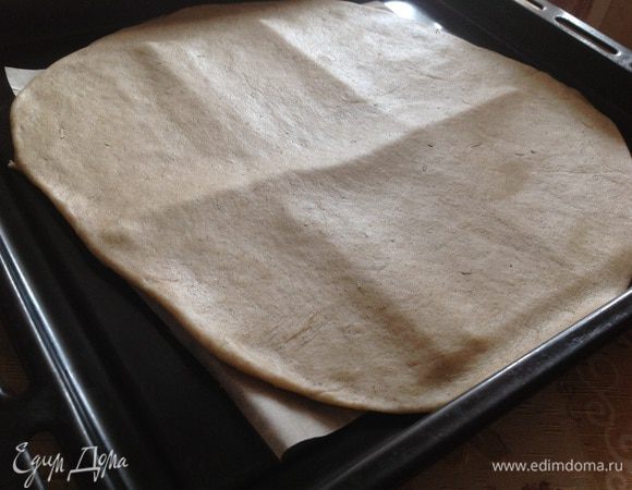 Тесто очень тонко раскатать на рабочей поверхности, присыпанной мукой. Потом аккуратно перенести на противень, застеленный бумагой для выпечки. 