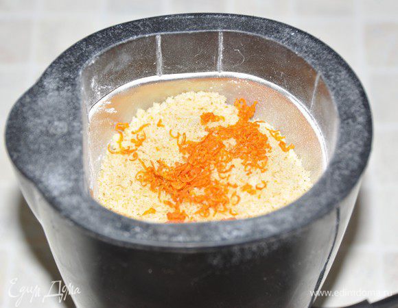 Обрезки бисквита измельчить сначала в блендере. Получилась красивая яркая желтая крошка. Но мы ещё добавим оранжевый цвет. Небольшими партиями дополнительно измельчим крошку бисквита с подсушенной апельсиновой цедрой (помните мы оставляли 2,5 столовой ложки подсушиваться?) в кофемолке. 
Получилось «солнечная» бисквитная крошка.
