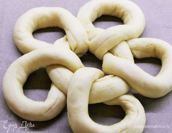 Постелите лист пергамента и поместите на него первое кольцо. Скрутите первое кольцо по центру и защипните. К центральному кольцу присоедините  еще пять колец, защипните так, чтобы шов оказался внизу.

