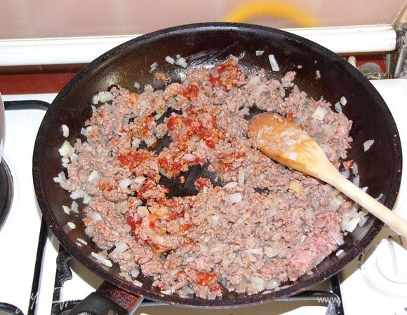 Лук мелко режем и обжариваем на масле в сковороде. Добавляем фарш и обжариваем еще пару минут. Потом наступает очередь томатной пасты, ее тоже надо обжарить вместе с фаршем. 