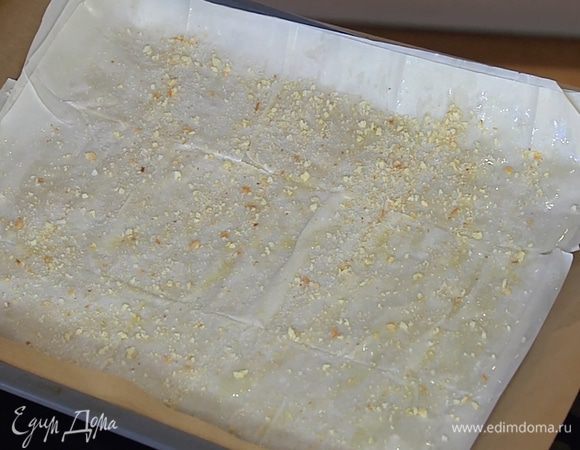 Противень выстелить бумагой для выпечки и уложить один на другой три листа фило, слегка смазывая каждый при помощи кисточки оливковым маслом. Первый и третий слои теста присыпать панировочными сухарями.