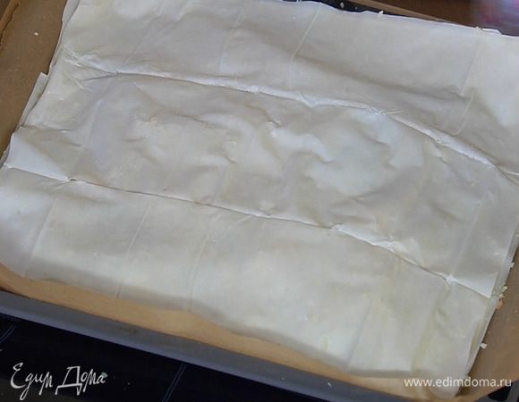 Накрыть начинку двумя листами фило, смазав их оливковым маслом. Присыпать сверху домашними сухарями, затем уложить оставшийся лист фило.