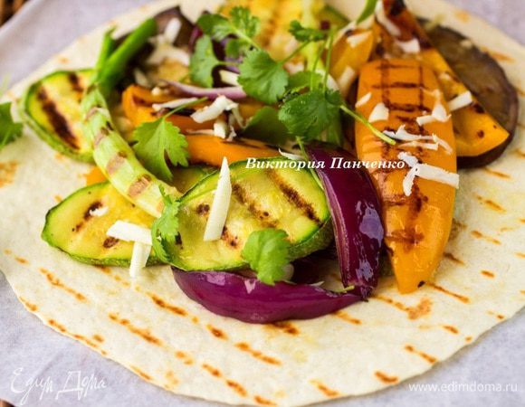 На каждую выложить горку овощей, посыпать брынзой, натертой на крупной терке, добавить веточки кинзы и базилика.