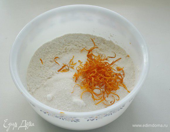 Просейте муку, добавьте сахар, разрыхлитель, соль, и цедру одного  апельсина. 