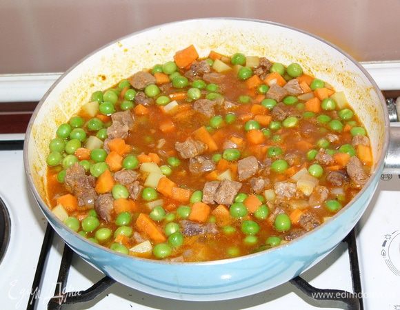 Как только мясо стало мягким, добавляем нарезанные овощи и горошек, при необходимости подливаем горячей воды. Тушим еще 15 минут. Солим.