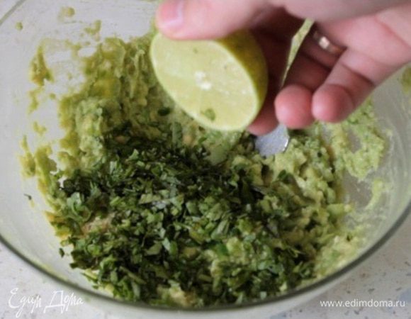 Далее делаем соус гуакамоле. Мякоть авокадо давим в пюре, добавляем туда мелко нарезанную кинзу и чили перец, сок половины лайма. Давим из 3-х зубчиков чеснока пюре и также добавляем к авокадо. Солим, перчим. Перемешиваем. Гуакамоле готов.