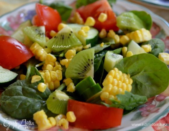 Разложим по тарелкам молодой помытый шпинат, либо можно заменить на салатный микс, такой как смесь руколы, шпината, молодых листьев салата. Помидор крупный разрезаем на несколько частей, кукурузу свежую очищаем от початка и срезаем острым ножом аккуратно желтые зерна, базилик листья свежие раскладываем по тарелкам, огурец тонко нарезаем, лук красный, киви  или манго очищаем и на кубики.