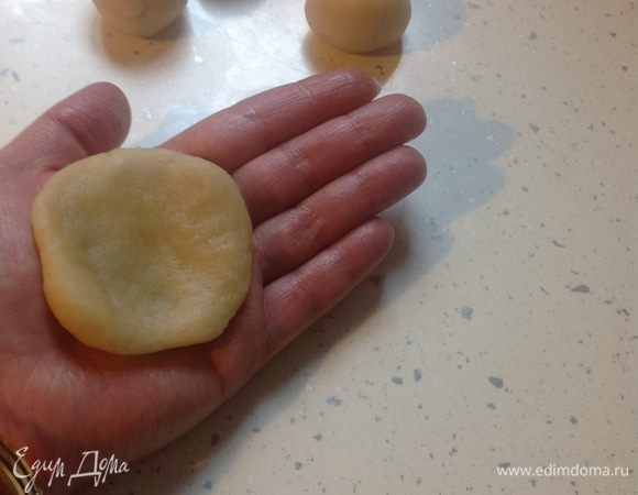 Теперь можно разделывать наши булочки. 
От теста отщипнуть кусочек величиной с грецкий орех или чуть больше, хорошо ладонями скатать шарик. Положить на середину полузакрытой ладони и ребром другой рукой надавить на шарик таким образом, чтобы получилась лепешка размером в пол ладони, слегка вогнутая по середине. 