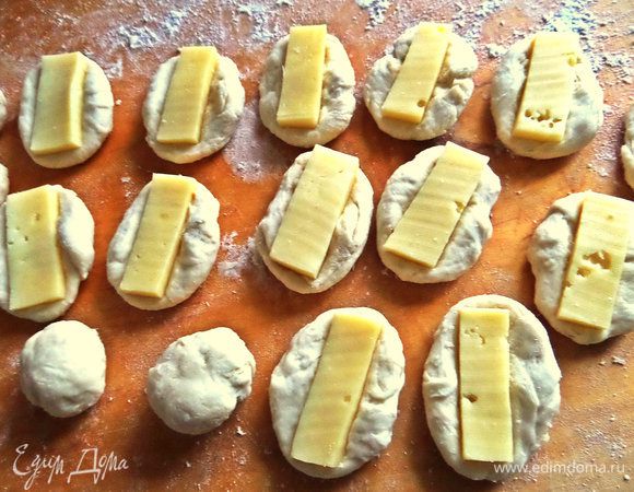 Из теста скатать шарик, приплюснуть и положить сыр на каждую заготовку.