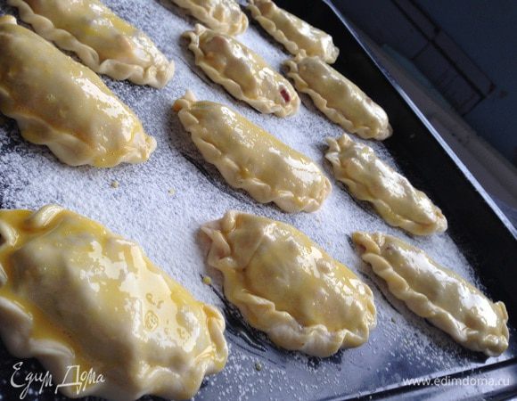 Выложить пирожки на противень, застеленный бумагой для выпекания или присыпанный мукой. Смазать их желтком, ещё можно посыпать кунжутом. Выпекать пирожки в предварительно разогретой духовке до 180 градусов, 25-30 минут. 