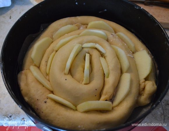 Вложить кусочки яблок между рулетами. Накрыть пирог полотенцем и поставить на расстойку на 20-30 минут.