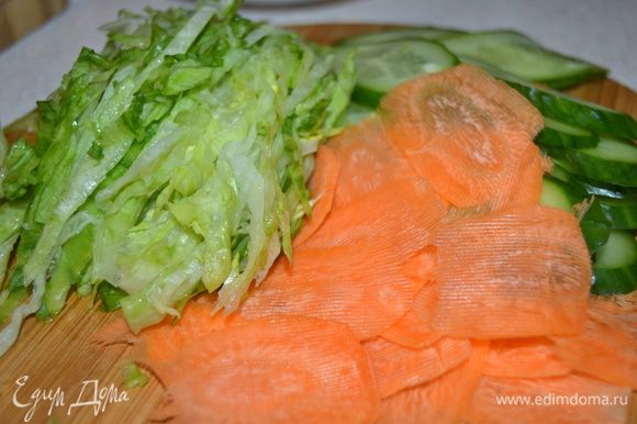 Огурец нарезать тонкими ломтиками, салат нашинковать (салат можно заменить на пекинскую капусту), морковь нарезать тонкими пластинами, удобно это сделать овощечисткой.