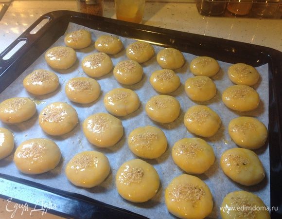 Наши заготовки выложить на противень, застеленный пекарской бумагой. Имейте ввиду, что в духовке булочки увеличатся в размере, поэтому плотно не укладывайте. Из этой пропорции обычно получается 1,5 больших противня для выпечки (для стандартной духовки шириной 60 см).
Приготовим смесь для смазки. В маленькой миске или стакане взбить вилкой 2 желтка с 1 ст. л. масла (лучше оливкового). Смазать этой смесью булочки. Сверху посыпать кунжутом, черным тмином (он хорошо сочетается с мясной начинкой) или маком. Также можно оставить без обсыпки - они и так будут вкусными и красивыми. 
** Если выпекать булочки, предварительно замороженные, то их также нужно выложить на противень, поставить в духовку при 150 градусах минут на 10. Затем вытащить противень, смазать и обсыпать как указано выше и вернуть в духовку уже на 180 градусов до готовности. Не смазывайте яйцом холодное тесто, так как оно частично впитается и блеска не будет. Также замороженную поачу лучше вынуть из морозилки и переложить в холодильную камеру на ночь для медленной разморозки, а утром печь как обычно. 