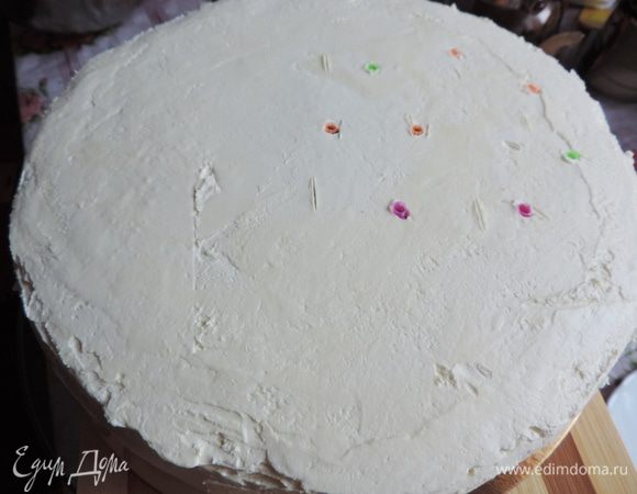 Кладем нижний ярус на подложку, обмазываем его кремом и выравниваем.
Теперь нам надо усилить нашу конструкцию, чтоб нижний ярус не прогнулся под весом верхнего и не испортил нам праздник. 
В этот раз я использовала коктейльные трубочки. По моей задумке верхний ярус стоит на краю нижнего. Протыкаем трубочкой нижний ярус в месте, где будет стоять верхний этаж. Затем ее вынимаем и отрезаем от нее длину, равную отмеренной высоте торта. Отрезаем еще 5-6 кусочков такой же длинны. Втыкаем их по периметру намеченного места верхнего яруса.