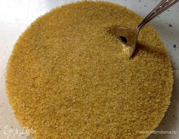 Высыпать в глубокую миску булгур.
** Для этого блюда необходимо взять именно булгур мелкого помола. На фото видно, какого размера должны быт крупинки по отношению к чайной ложке.