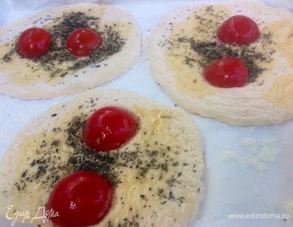 Выкатываем лепешки небольшого размера, поливаем их чуть оливковым маслом, посыпаем итальянскими травами, один помидор черри режем пополам (желательно брать сладкие черри) и слегка вдавливаем половинки черри в лепешку.
