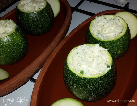 Смазать форму для запекания оливковым маслом, выложить цукини, начинив их и посыпав тертым сыром.

Я запекала в своих любимых глиняных тарелочках, предварительно замочив их на 10 минут в холодной воде.