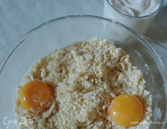 К образовавшейся крошке добавить желтки и сметану, ванильный сахар, разрыхлитель (или соду погасить уксусом).