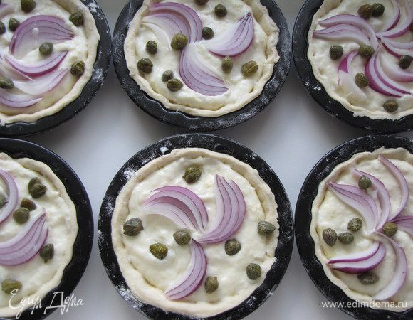 В каждую форму выложить 1 ст. л. сырно-яичного соуса (или больше, в зависимости от размера формочек), дольку лука и немного каперсов.