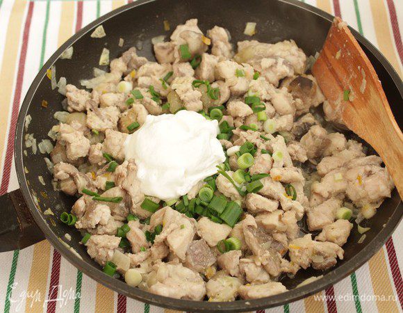 Добавьте рыбу и быстро обжарьте, аккуратно перемешивая, 3-5 мин.  Мелко нарежьте зеленый лук и добавьте его к рыбе вместе со сметаной, немного потушите. Остудите до комнатной температуры.