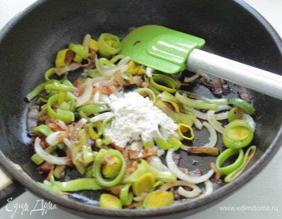 Добавляем лук и жарим, помешивая, около 5 минут. Затем добавляем ложку муки и жарим, помешивая, 1 минуту.