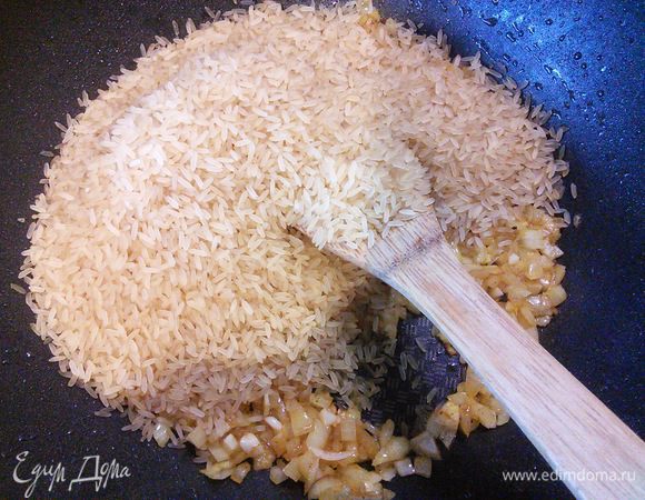 В той же сковороде где обжаривался кролик глазируем лук с чесноком до прозрачности, добавляем рис и обжариваем его в течении 2 мин. 