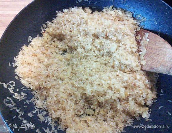 Рис обволакивается маслом и ароматом лука и чеснока и становится прозрачным. 