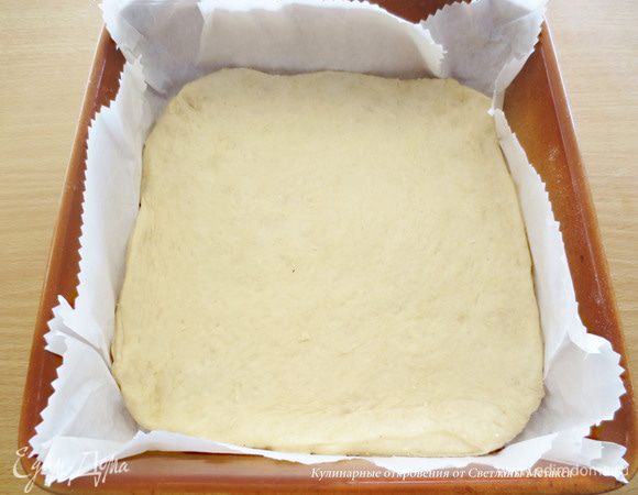 Готовое тесто разделить на 2 части, одна из которых будет чуть больше другой. Если Вы будите использовать прямоугольную форму, а не квадратную как у меня (25 см), то для основы пирога, оставьте теста вдвое больше, чем на вторую часть, которая пойдет на  оформление пирога.
Из большой  части теста  раскатать пласт, толщиной 8 мм. Форму застелить бумагой для выпечки  и положить на дно формы раскатанный пласт теста.