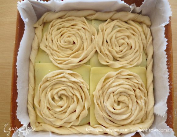    Из оставшегося теста раскатать более тонкий пласт, нарезать полоски 1-2 см шириной и 40 см доиной и закрутить спиральки, укладывая их на каждый пласт сыра. 
Для ободка пирога, используем спираль из полосок шириной 3 см Это нужно для того, чтобы края пирога получились закрытыми, так как их не залепляем. 
Яичный желток взбиваем и смазываем пирог. Оставляем на 10 минут и затем выпекаем при температуре 200 градусов примерно 40 минут. Время выпечки регулируйте в зависимости от Вашей духовки.