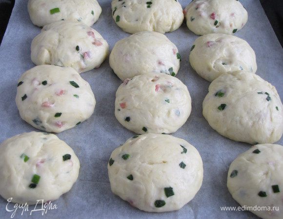 Разделить тесто на кусочки размером с яйцо и скатать из них шарики. Застелить противень бумагой для выпечка, смазанной маслом. Положить булочки,накрыть полотенцем и оставить на 30 минут.