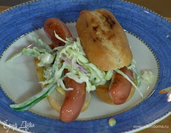 Две половинки обжаренных булочек слегка смазать майонезом, выложить на каждую из них сосиску, сверху поместить салат и накрыть оставшимися половинками булочек.