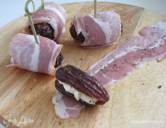 Полоски бекона поперчить по вкусу и завернуть в них финики. Сколоть шпажкой или зубочисткой.