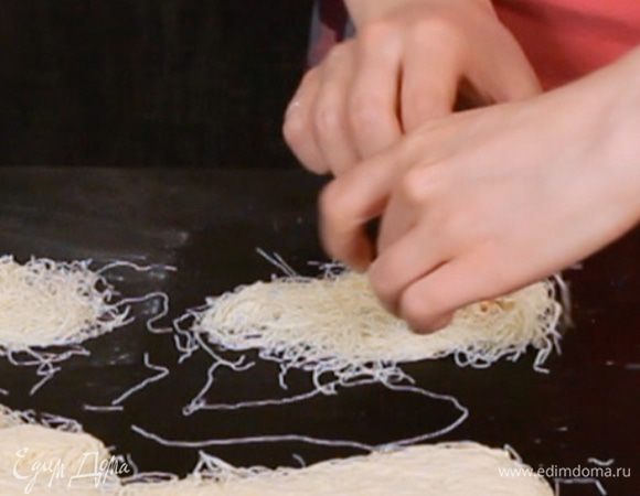 Тесто катаифи разделить на полоски. Обвалять кусочки сыра в оставшемся крахмале и завернуть в рулетик.