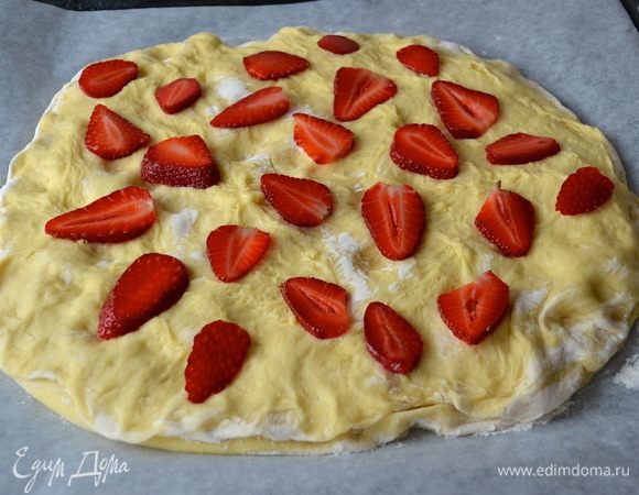Теперь снимите верхний лист пергамента со второго коржа и аккуратно перенесите, накрыв им корж с джемом. Снимите нижний лист бумаги и слегка скрепите края по кругу. Подушечками пальцев сделайте на верхнем корже небольшие углубления (как это обычно делают с фокаччей!) Нарежьте пластинами вымытую и высушенную клубнику. Присыпьте поверхность немного коричневым сахаром и поставьте в разогретую духовку.